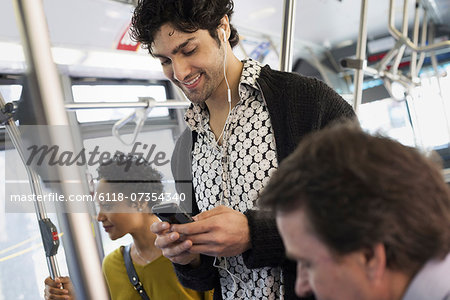 New York City park. People, men and women on a city bus. Public transport. Keeping in touch. A young man checking his cell phone.