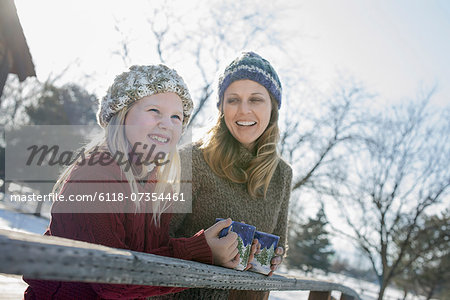 Winter scenery with snow on the ground. A child and an adult having a hot drink on a cold day.