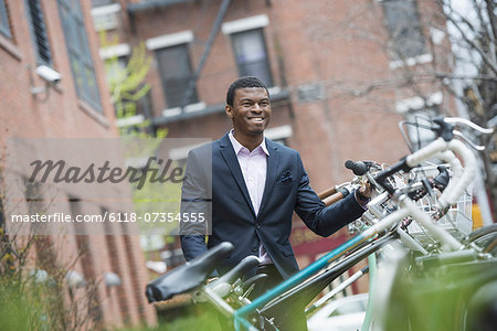 City life in spring. A man in a blue suit, by a bicycle rack in a city park.