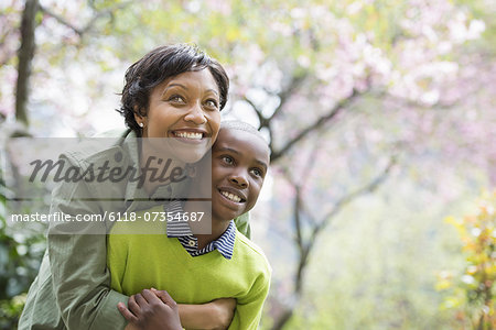 A New York city park in the spring. Sunshine and cherry blossom. A mother and son hugging and laughing.