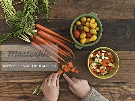 A person preparing fresh vegetables on a wooden table.