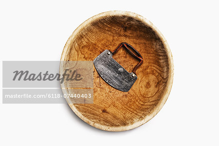 A well worn wooden chopping bowl, with a steel blade and handle.