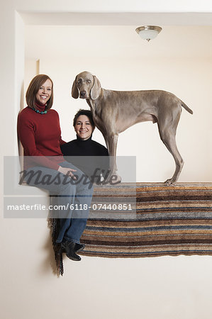A same sex couple, two women posing with their Weimaraner pedigree dog.