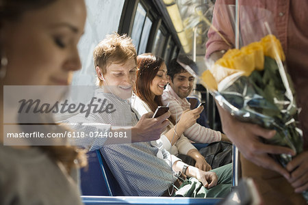 Urban Lifestyle. A group of people, men and women on a city bus, in New York city. Two people checking their smart phones.