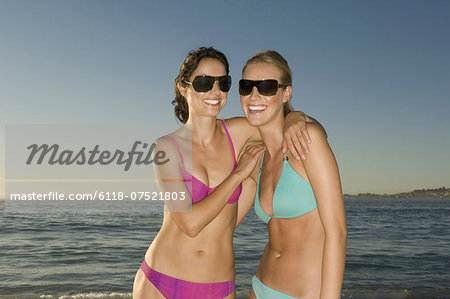 Two young women on the beach in Cape Town, wearing bikinis and sunglasses.