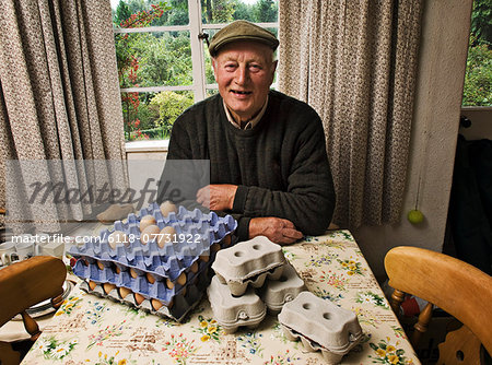 A farmer seated at a table in a farmhouse with trays of fresh eggs.