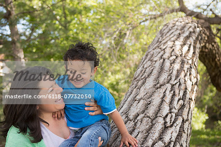 A mother and son in the park in Santa Fe, by a tall tree.