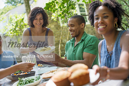 A family gathering, men, women and children around a table in a garden in summer.