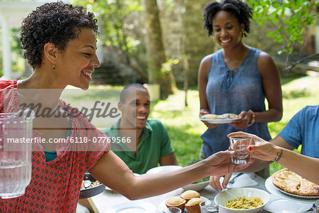 A family gathering, men, women and children around a table in a garden in summer.