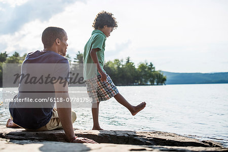 A father and son on a lake shore in summer.