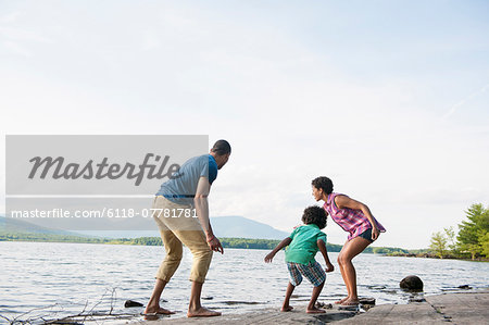 A family, mother, father and son playing on the shores of a lake.