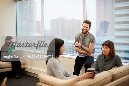 Three people by a window in an office, two women and a man.