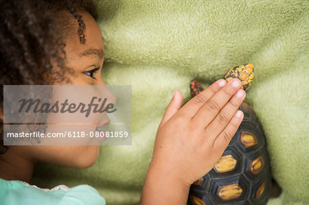 A young girl looking closely at a tortoise.