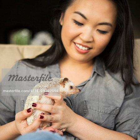 A woman holding a hedgehog in her hands.