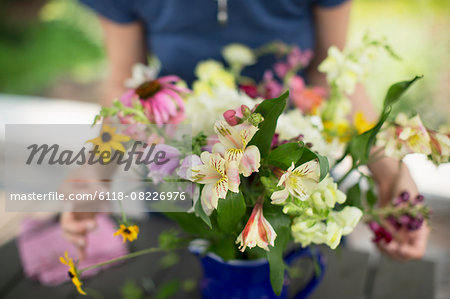 A person arranging a bunch of flowers in a vase.