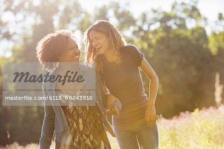 Two women walking through a field talking and laughing.