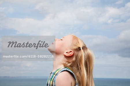 A young girl raising her face to the sun.