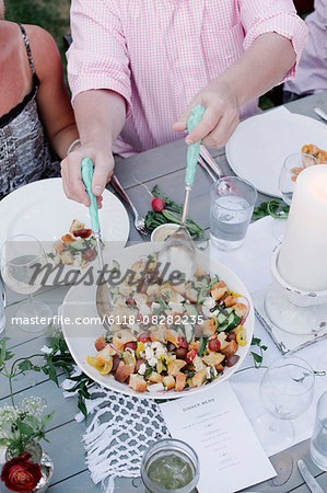 People around a table at a garden party, a bowl of salad.
