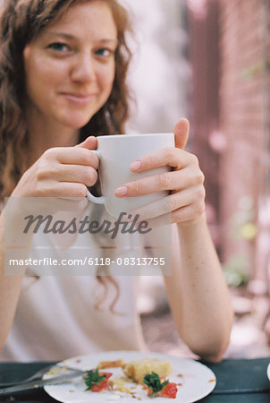 Smiling woman holding a white china teacup.