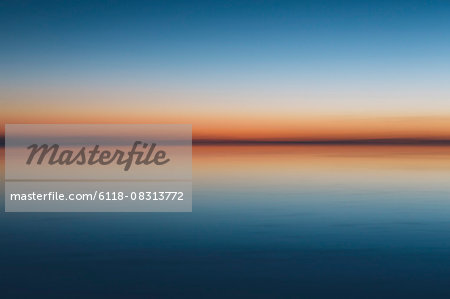 The view to the clear line of the horizon where land meets sky, across the flooded surface of Bonneville Salt Flats. Dawn light,