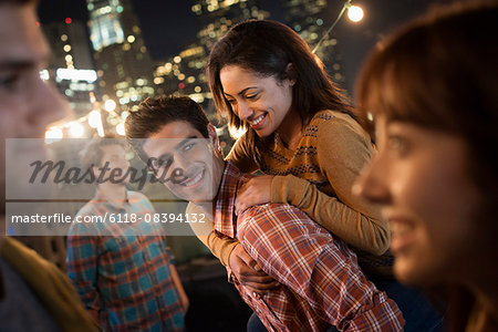 A group of men and women at a rooftop party with a view over the city.