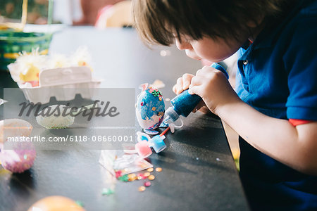 A child decorating eggs at Easter with glitter, glue and paint.