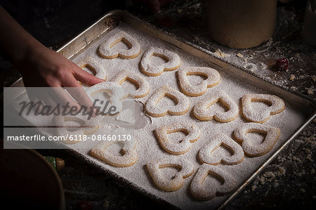 Valentine's Day baking, woman arranging heart shaped biscuits on a baking tray.