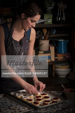 Valentine's Day baking, young woman standing in a kitchen, with a baking tray of heart shaped biscuit.