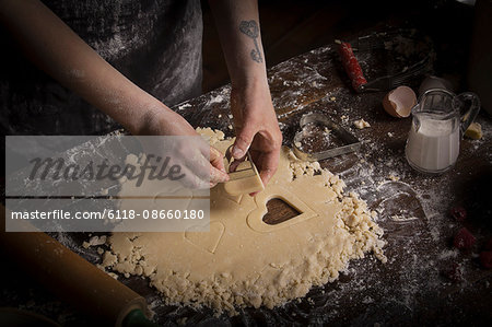 Valentine's Day baking, woman cutting out heart shaped biscuits from dough.
