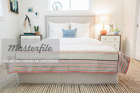 A bedroom in an apartment with a double bed and a retro look antique patterned patchworked bed cover.