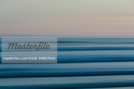 Ocean waves and the view to the horizon over the sea at dusk from the beach.