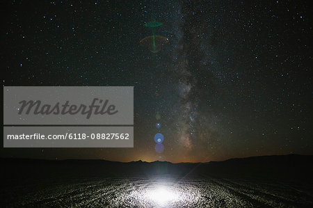 Glowing bright light on playa, night sky and Milky Way above, Black Rock Desert, Nevada