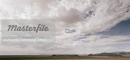 Numbers on a wall in a desert landscape with mountains in the distance.