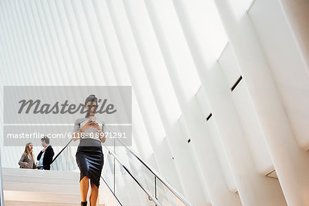 A woman walking down a staircase in the Oculus building, the World Trade Centre hub, modern architectural design with a ribbed vaulted roof space.