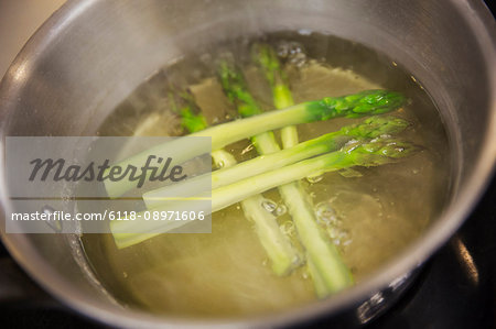 Close up high angle view of green asparagus spears in a pot of water.