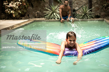 A boy floating on a pool raft in a swimming pool.