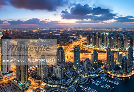 Aerial view of the cityscape of Dubai, United Arab Emirates at dusk, with skyscrapers and the marina in the foreground.