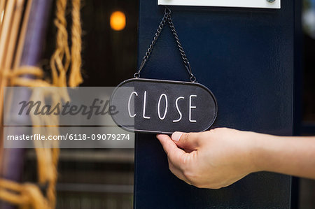 Close up of person turning closed sign on glass door to a bakery