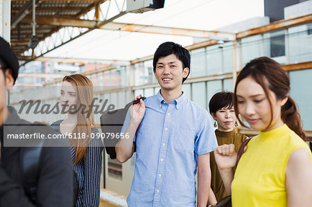 Small group of people standing on the platform of a subway station, Tokyo commuters.