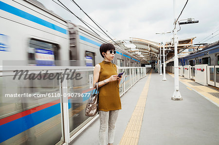 Woman wearing sunglasses standing on the platform of a subway station, Tokyo commuter.