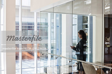 Businesswoman standing in a conference room window in a large business centre.