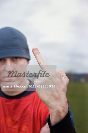 Caucasian man giving the viewer the finger as an obscene gesture.