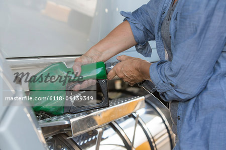 Caucasian woman truck driver filling truck with diesel fuel at a truck stop.