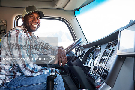 Black man truck driver in the cab of his commercial truck. Black man truck driver in the cab of his commercial truck.