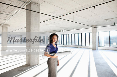 Black woman architect standing in a large empty raw office space.