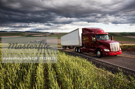 commercial truck driving though wheat fields of eastern Washington, USA at sunset.