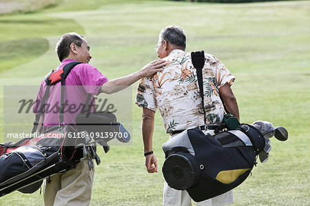 Two senior friends golfing and walking on a fairway toward their next shots.
