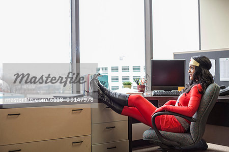 A black office superhero business woman sits in her office and ponders her next business move.