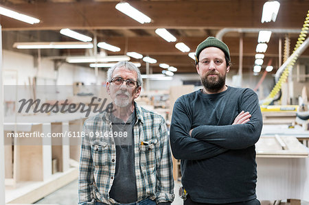 Portrait of two Caucasian carpenters in a large woodworking factory.