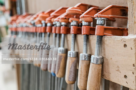 Close up of small bar clamps being used in a woodworking factory.